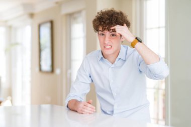 Kıvırcık saçlı genç iş adamı alnındaki sivilceden mutsuz olduğunu gösteriyor, siyah başlıklı çirkin bir enfeksiyon. Sivilce ve deri problemi