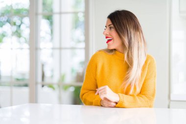 Evde kış kazak giyen genç güzel kadın uzak tarafına yüzünde, doğal ifade gülümseme ile arıyorum. Kendine güvenen gülüyor.