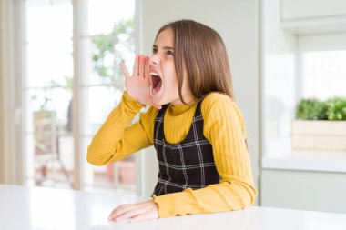 Genç, güzel sarışın kız evde sarı süveter giyip el ele tutuşarak bağırıyor ve bağırıyordu. İletişim konsepti.