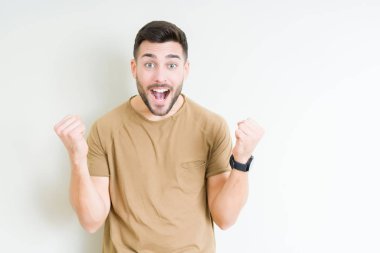 İzole arka plan kutlama üzerinde genç yakışıklı adam şaşırttı ve başarı için kaldırdı kollarını açarak hayret ve gözleri açık. Kazanan kavramı.