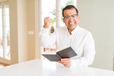 Orta yaş adam evde gözlük giyen bir kitap okuma sinirli ve sinirli öfke ile bağırarak, deli ve yükseltilmiş el ile bağırıyor, öfke kavramı