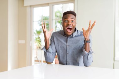 Afro-Amerikan yakışıklı beyaz masa kaldırdı Kollarını açarak deli ve başarı için hayran kutluyor ve açık gözleri heyecanlı çığlık. Kazanan kavramı