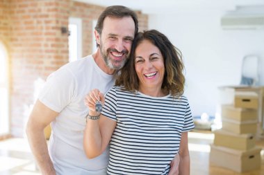 Orta yaş Senior romantik çift Holding ve yeni bir eve taşımak için mutlu gülümseyen ev anahtarlarını gösteren