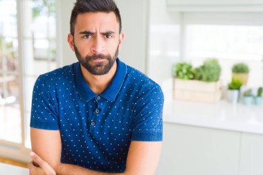 Evde yakışıklı İspanyol adam şüpheci ve sinir, kesişen silah ile yüz üzerindeki ifade onaylamaz. Negatif kişi.