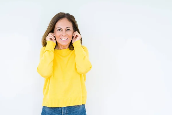 大音量の音楽の騒音に対して 耳を指で覆う孤立した背景の上に黄色いセーターを着た美しい中年女性 ろうの概念 — ストック写真