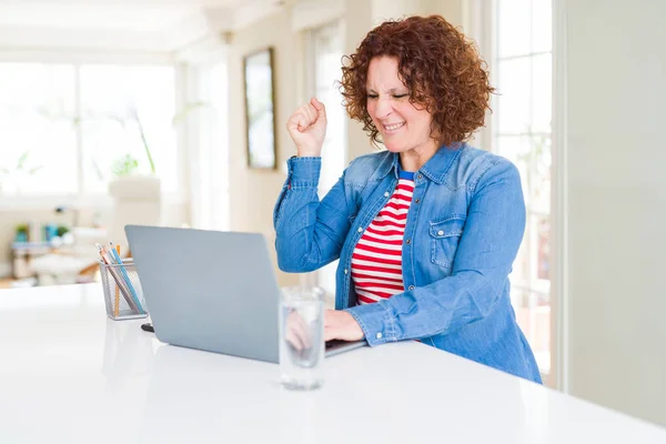 컴퓨터 노트북을 사용하여 일하는 시니어 여성은 자랑스럽게 비명을 지르며 승리와 — 스톡 사진