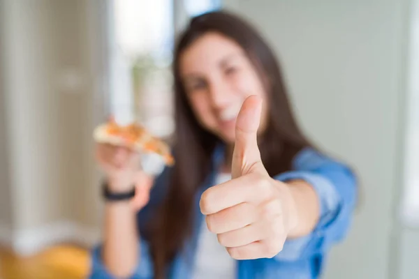 美丽的年轻女子吃一片美味的比萨饼快乐与大微笑做Ok标志 拇指用手指 优秀的标志 — 图库照片