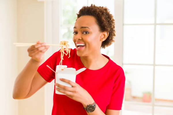 Beautiful young african american woman eating noodles using choo — Stock Photo, Image