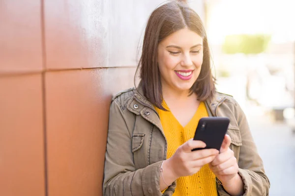 Mulher Bonita Sorrindo Positivo Usando Smarpthone Inclinado Uma Parede Cidade — Fotografia de Stock