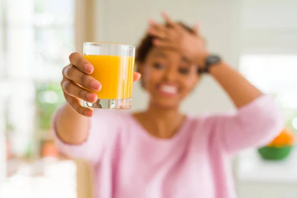 若いアフリカ系アメリカ人女性煮沸オレンジ ジュース自宅恥と驚き顔 怒っているとイライラとショックの頭の上の手で重点を置かれました 恐怖と動揺の間違い — ストック写真