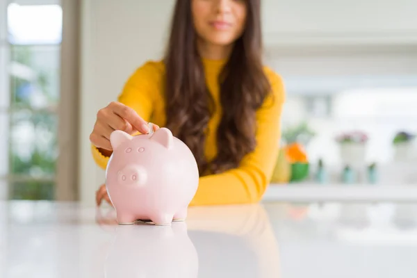 Close up de mulher sorrindo colocando uma moeda dentro do banco porquinho como em — Fotografia de Stock