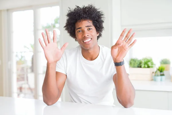 自信と幸せ笑みを浮かべている間 若いアフリカ系アメリカ人の男性は カジュアルな白いTシャツを着て家に座って指の番号9で示すと指摘 — ストック写真