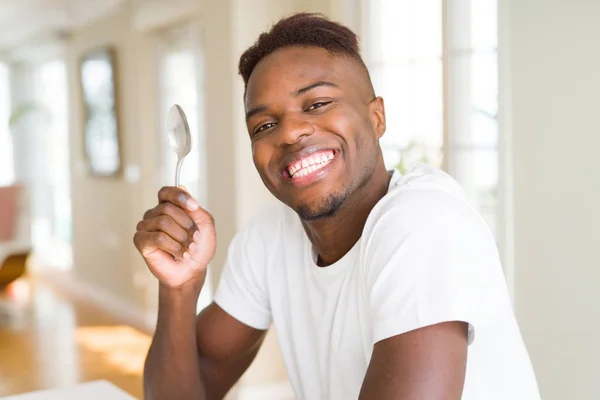 Pohledný Afričan držící stříbrnou lžíci s úsměvem — Stock fotografie