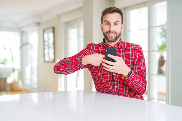 Przystojny Człowiek Pomocą Smartfona Zaskoczeniem Twarzy Palcem Skierowanym Siebie — Zdjęcie stockowe