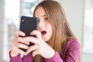 Şaşırtıcı bir yüz ile şok korkuyor akıllı telefon kullanarak bir mesaj Gönderen güzel genç kız çocuk, korku ve heyecanlı ifade ile heyecan