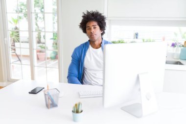 Afro-Amerikan adam yüzünde ciddi ifade ile bilgisayar kullanarak çalışıyor. Kameraya basit ve doğal bir bakış.