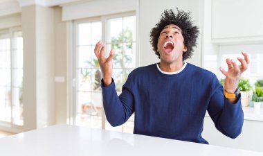 Sıradan bir kazak giyen genç Afro-Amerikan erkeği kollarını kaldırıp heyecanla haykırarak başarıyı kutluyor. Kazanan konsept