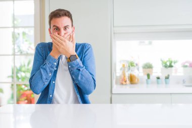 Evde yakışıklı adam yanlışlık için eller ile ağız kapsayan şok. Gizli konsept.