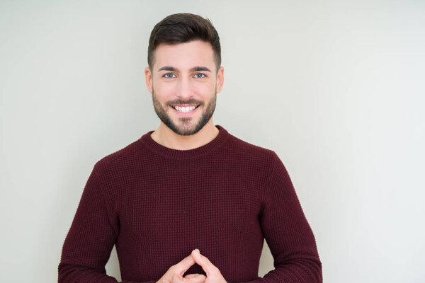 Young handsome man wearing a sweater over isolated background Hands together and fingers crossed smiling relaxed and cheerful. Success and optimistic