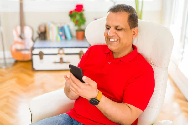 Hombre de mediana edad sonriendo alegre blanco usando teléfono inteligente sentado o —  Fotos de Stock