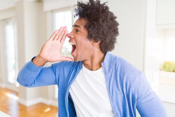 Hombre Afroamericano Casa Gritando Gritando Fuerte Lado Con Mano Boca —  Fotos de Stock