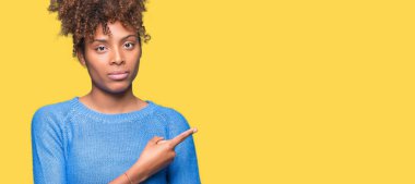 Güzel genç Afro-Amerikan kadın yüzünden izole reklam, ciddi ve sakin yüz gösterilen yan el parmak ile işaret arka plan