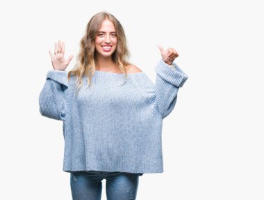 Güzel sarışın genç kadın giyiyor kış kazak gösterilen ve parmakları ile işaret izole arka plan üzerinde kendinden emin ve mutlu gülümseyerek süre 6 numara.