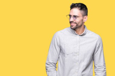 Genç yakışıklı adam uzak tarafına yüzünde, doğal ifade gülümseme ile seyir izole arka plan üzerinde güneş gözlüğü takıyor. Kendine güvenen gülüyor.