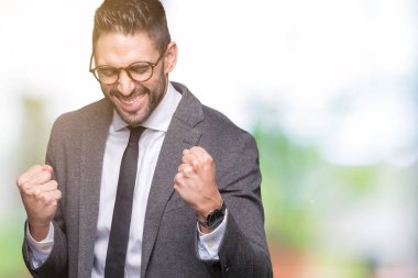 Gülümseyen ve başarı için çığlık genç yakışıklı iş adamı izole arka plan çok mutlu ve heyecanlı kaldırdı, silah ile kazanan jest yapıyor üzerinde. Kutlama kavramı.