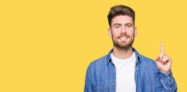 Casual kot giyen genç yakışıklı sarışın adam başarılı fikirle yukarı işaret parmağı ceket. Çıktıktan ve mutlu. Bir numara.