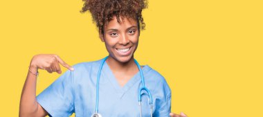 Yüzünde gülümseme ile kendinden emin görünüyorsun, kendini gururlu ve mutlu parmakları ile işaret izole arka plan genç Afro-Amerikan doktor kadın.