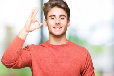 Gülümseyen izole arka plan üzerinde genç yakışıklı adam el ve parmaklar ok işaretiyle yapıyor olumlu. Başarılı ifade.