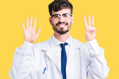 Genç profesyonel bilim adamı adam izole arka plan üzerinde beyaz ceket giyiyor gösteren ve parmak numarası sekiz ile işaret kadar emin ve mutlu gülümseyen.