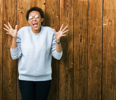 Genç güzel Afrikalı-Amerikalı kadın üzerinde gözlük takan arka plan deli kutluyor izole ve crazy arms ile başarı için kaldırdı ve heyecanlı çığlık gözler kapalı. Kazanan kavramı