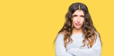 Yüz çapraz kolları olan kış kazak şüpheci ve sinir, onaylamayan ifade giyen genç güzel kadın. Negatif kişi.