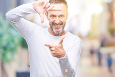 Elle yapma çerçeve ve parmakları ile mutlu yüz gülümseyen izole arka plan üzerinde beyaz t-shirt giyen orta yaş ağarmış komuta sizde. Yaratıcılık ve Fotoğrafçılık kavramı.