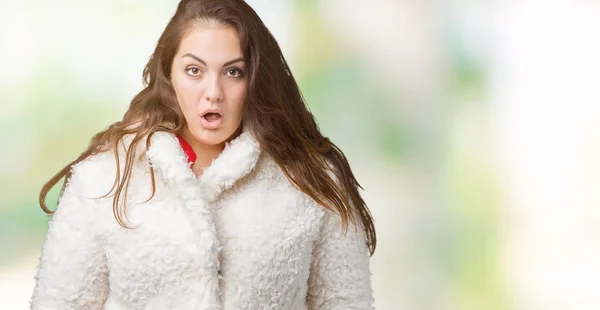 プラスサイズの若い女性は美しい冬羊コートを身に着けている分離された背景を恐れてと驚き式 恐怖と興奮した顔でショックを受けた — ストック写真