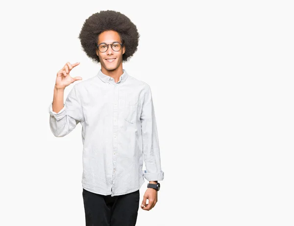 メガネをかけたアフロの髪をしたアフリカ系アメリカ人の男性笑顔で自信を持って 手をジェスチャと カメラを見ながら指でサイズの看板 メジャーコンセプト — ストック写真
