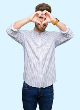 Genç yakışıklı adam el ve parmakları ile kalp şekli yapmak işareti bakarak gülümseyerek