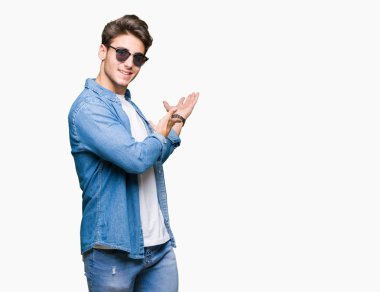 Yakışıklı delikanlı açık el ile doğal gülümseyen girmek için davet izole arka plan üzerinde güneş gözlüğü takıyor