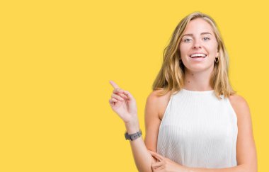 Yüzünde kocaman bir gülümseme ile izole arka plan üzerinde güzel genç zarif kadın kameraya bakarak yan el ve parmak ile işaret.