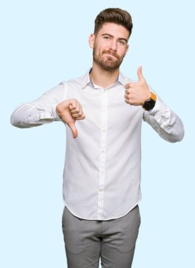 Genç yakışıklı iş adamı yapıyor başparmak yukarı ve aşağı, anlaşmazlık ve anlaşma ifade. Deli çatışma