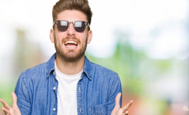 Genç yakışıklı zarif adam kot ceket giyen deli kutluyor ve kollarını kaldırdı ve açık gözleri heyecan çığlık ile başarı için hayran. Kazanan kavramı