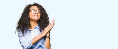 Kıvırcık saçlı Genç güzel iş kızı gözlük giyen alkışlar ve mutlu ve neşeli alkışlar, gülümseyen gururlu eller birlikte