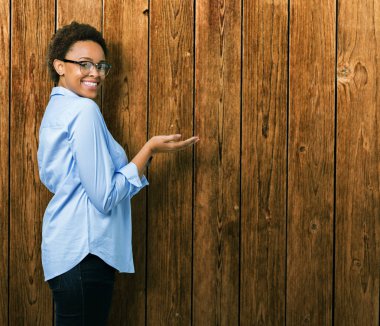 Genç güzel Afro-Amerikan iş kadını izole arka plan üzerinde el ve reklam mutlu ve kendinden emin gülümseyen sunulması avuç, yanında işaret