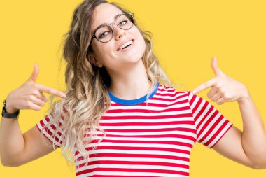 Yüzünde gülümseme ile kendinden emin görünüyorsun, kendini gururlu ve mutlu parmakları ile işaret izole arka plan üzerinde gözlük güzel sarışın genç kadın.