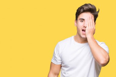 Yarım yüz, göz ve ağız el ile kapsayan yorgun esneme izole arka plan üzerinde beyaz t-shirt giyen genç yakışıklı adam. Acı yüzü acıyor.