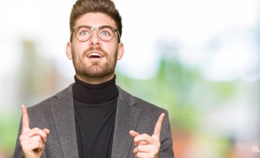 Gözlüklü genç yakışıklı iş adamı şaşırtmak ve yukarıya bakıp parmakları ile işaret şaşırttı ve silah kaldırdı.