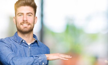 Casual denim gömlek eller eller büyük gösterilen ve büyük boy işareti, ölçü birimi sembolü ile giyen genç yakışıklı sarışın adam. Kameraya bakarak gülümsüyordu. Ölçüm kavramı.