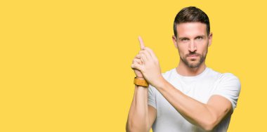 El hareketi ile sembolik silah tutan, çekim silah, kızgın yüz öldürme oynamak casual Beyaz tişört giyen yakışıklı adam